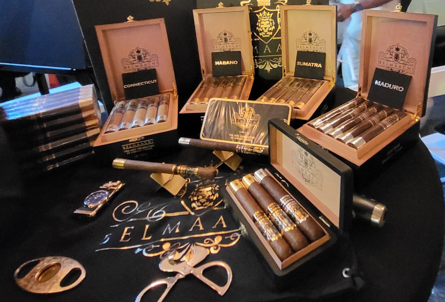 Compact Belmaachi booth setup in Atlanta with open cigar boxes showcasing four blends, Lanceros, and a luxury gift box.